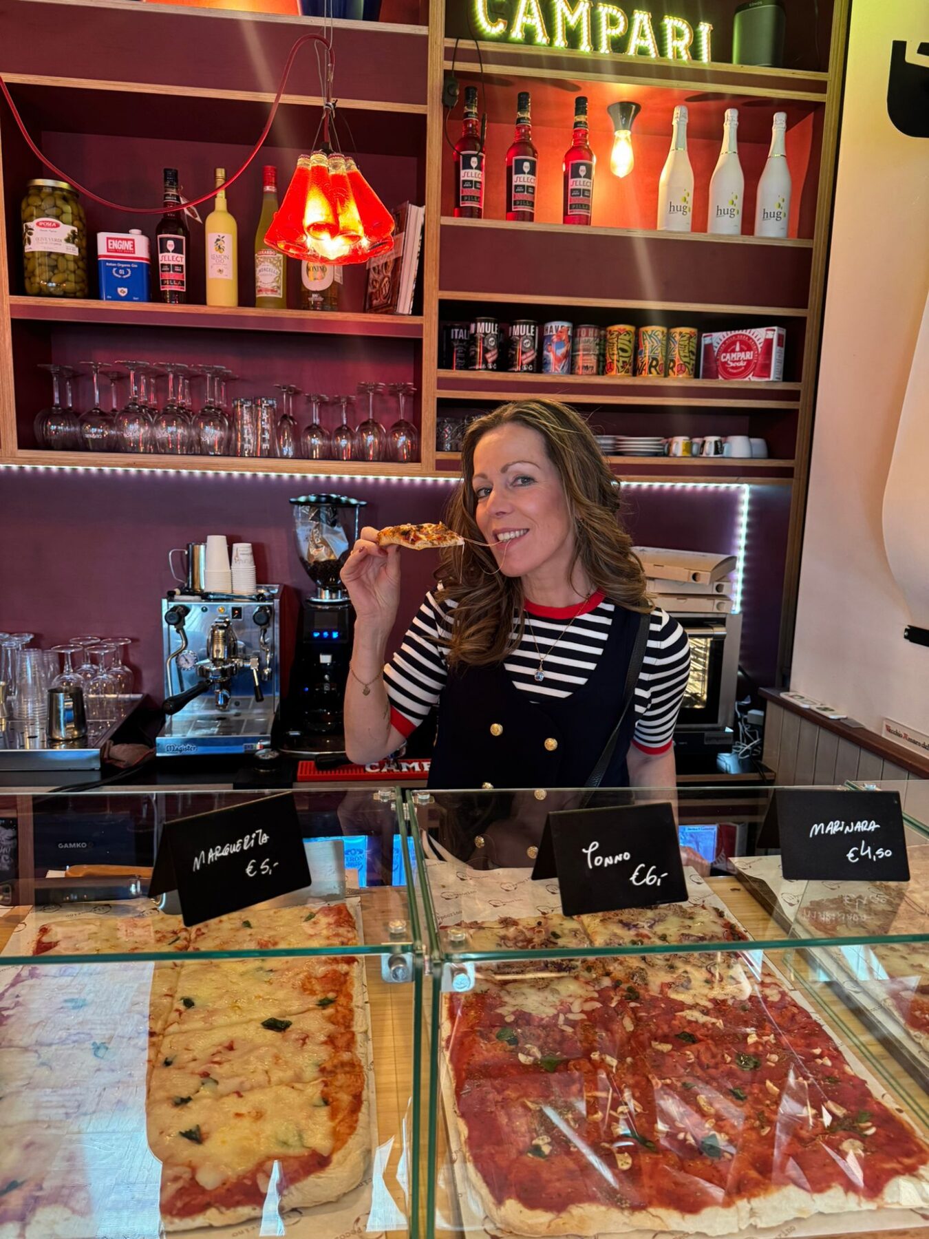 Tanya achter de toonbank van de Bottega met pizza al taglio