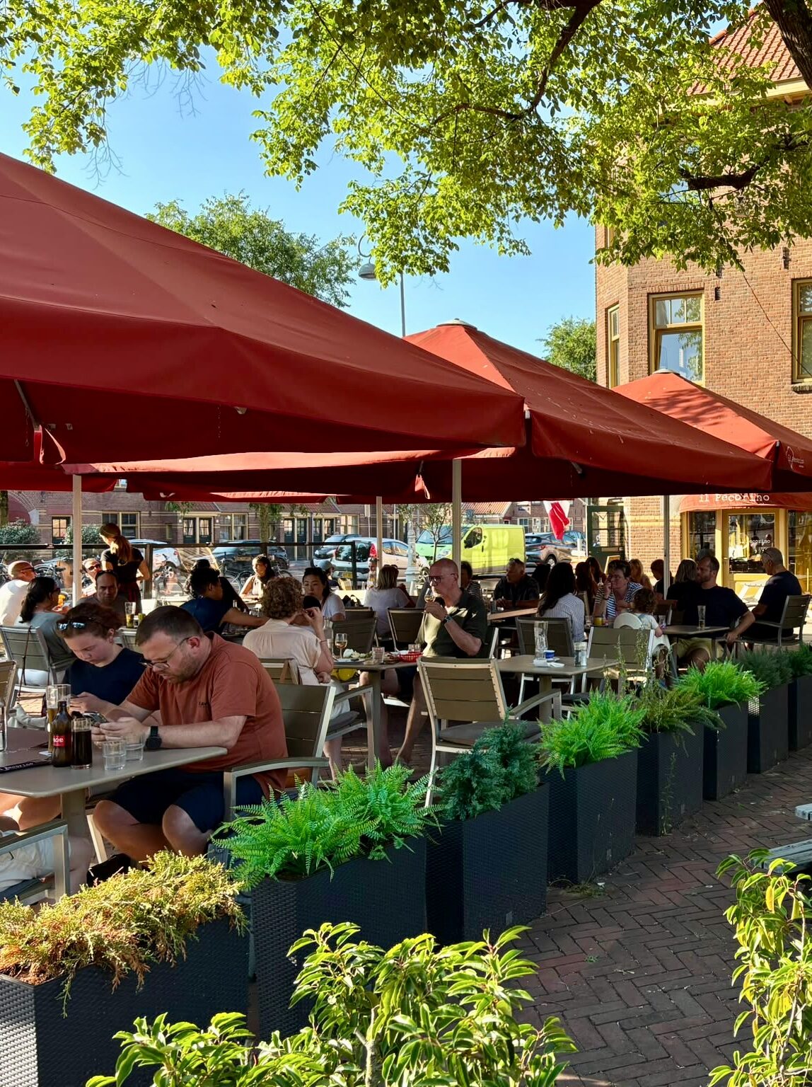 Het terras met rode parasols in de zon
